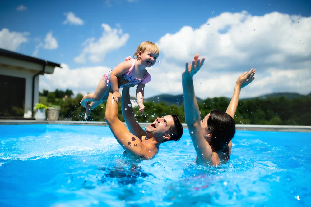 Young,Family,With,Small,Daughter,In,Swimming,Pool,Outdoors,In
